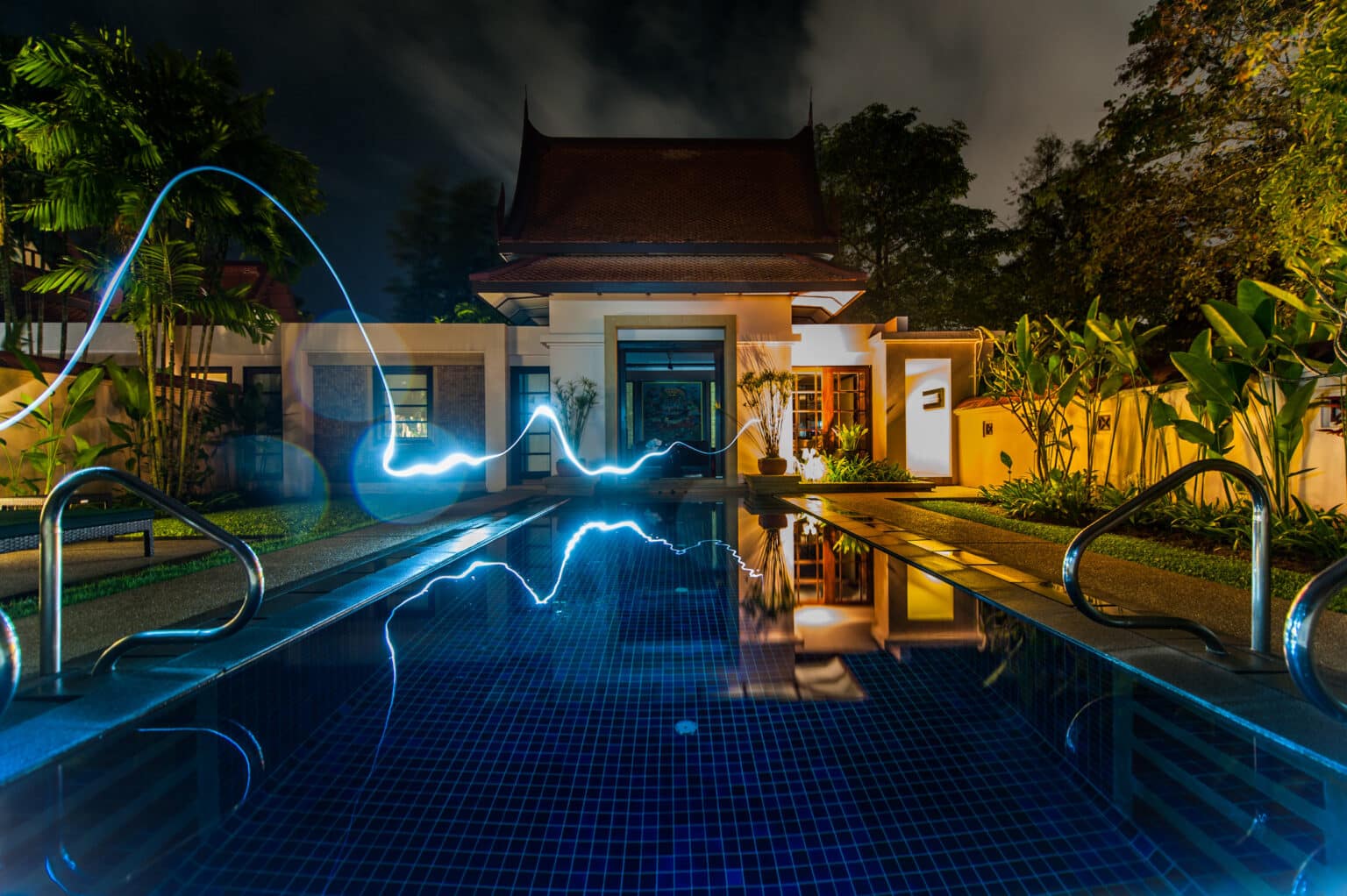 Luxury smart home with modern pool lighting at night, symbolizing energy automation and time-based smart control.