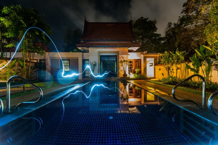 Luxury smart home with modern pool lighting at night, symbolizing energy automation and time-based smart control.