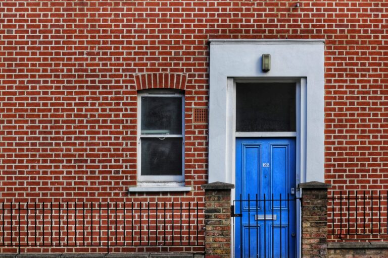 Front view of a brick rental property with a blue door, symbolizing the value added through home automation.