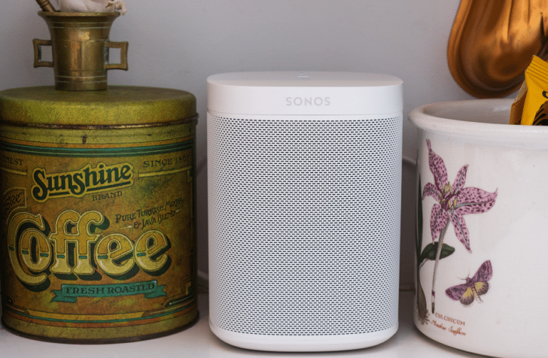 White Sonos speaker placed on a kitchen shelf, showcasing the integration of home audio systems into everyday spaces.