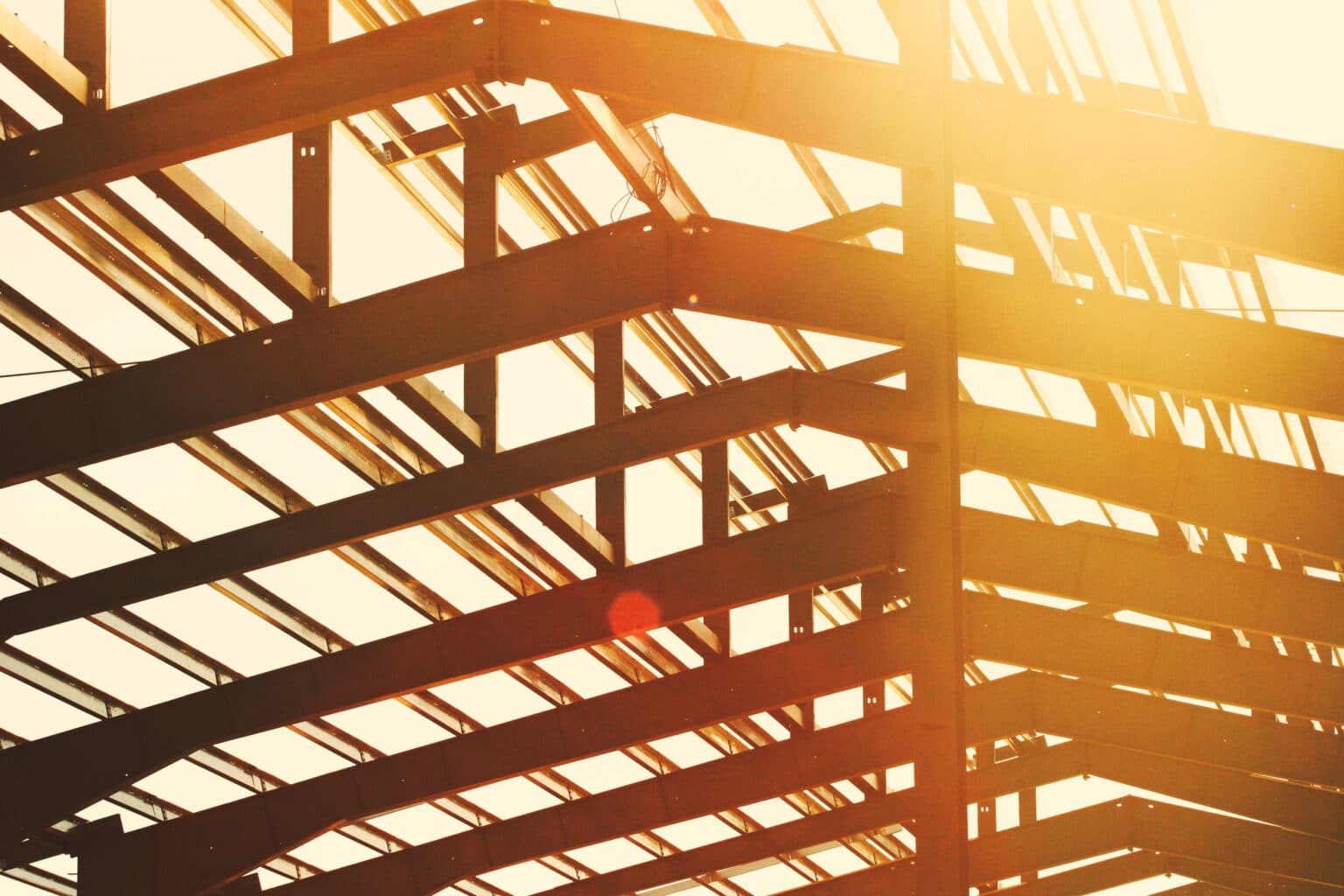 Steel framework of a building under construction at sunset, symbolizing growth and collaboration in smart home systems.