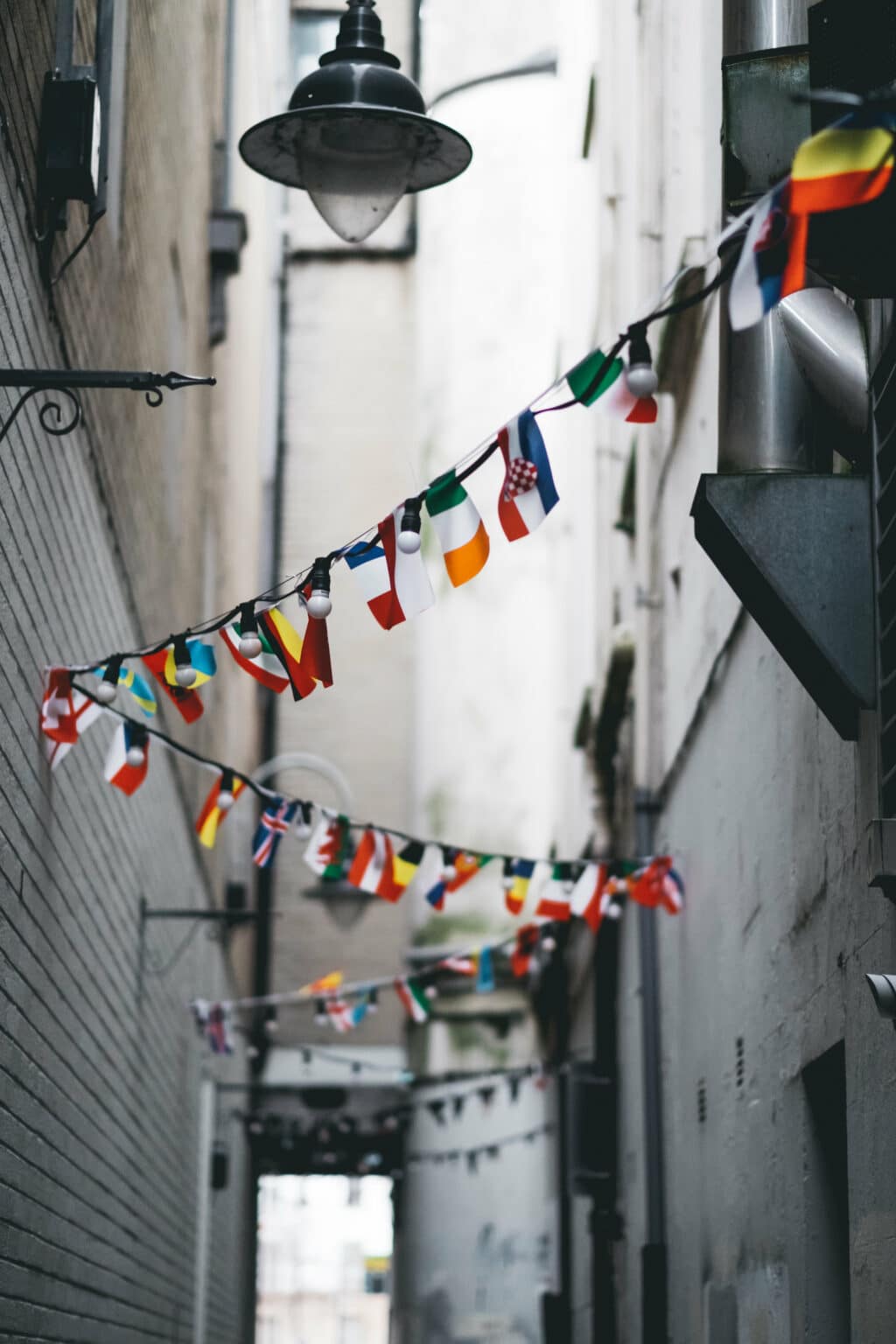 Strings of international flags hanging in an alleyway, symbolizing how smart home devices like Google Translate connect cultures at home.