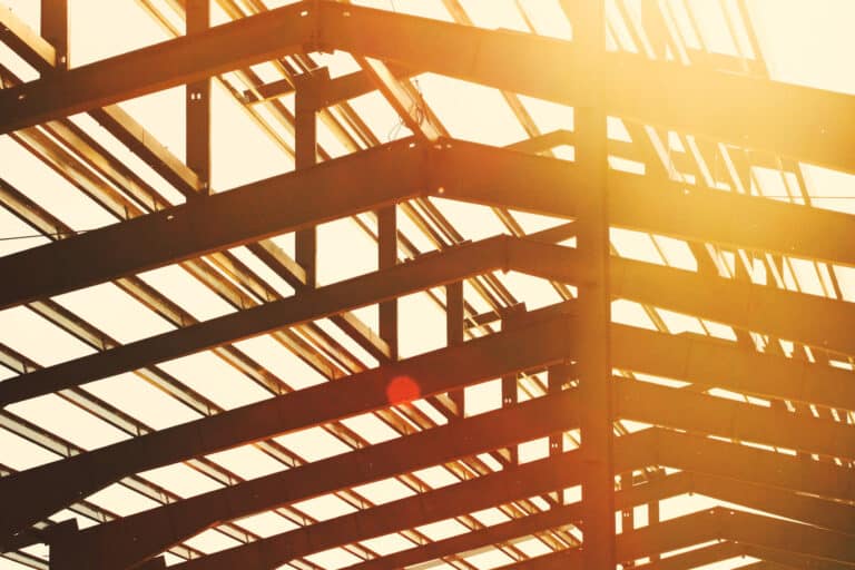 Steel framework of a building under construction at sunset, symbolizing growth and collaboration in smart home systems.
