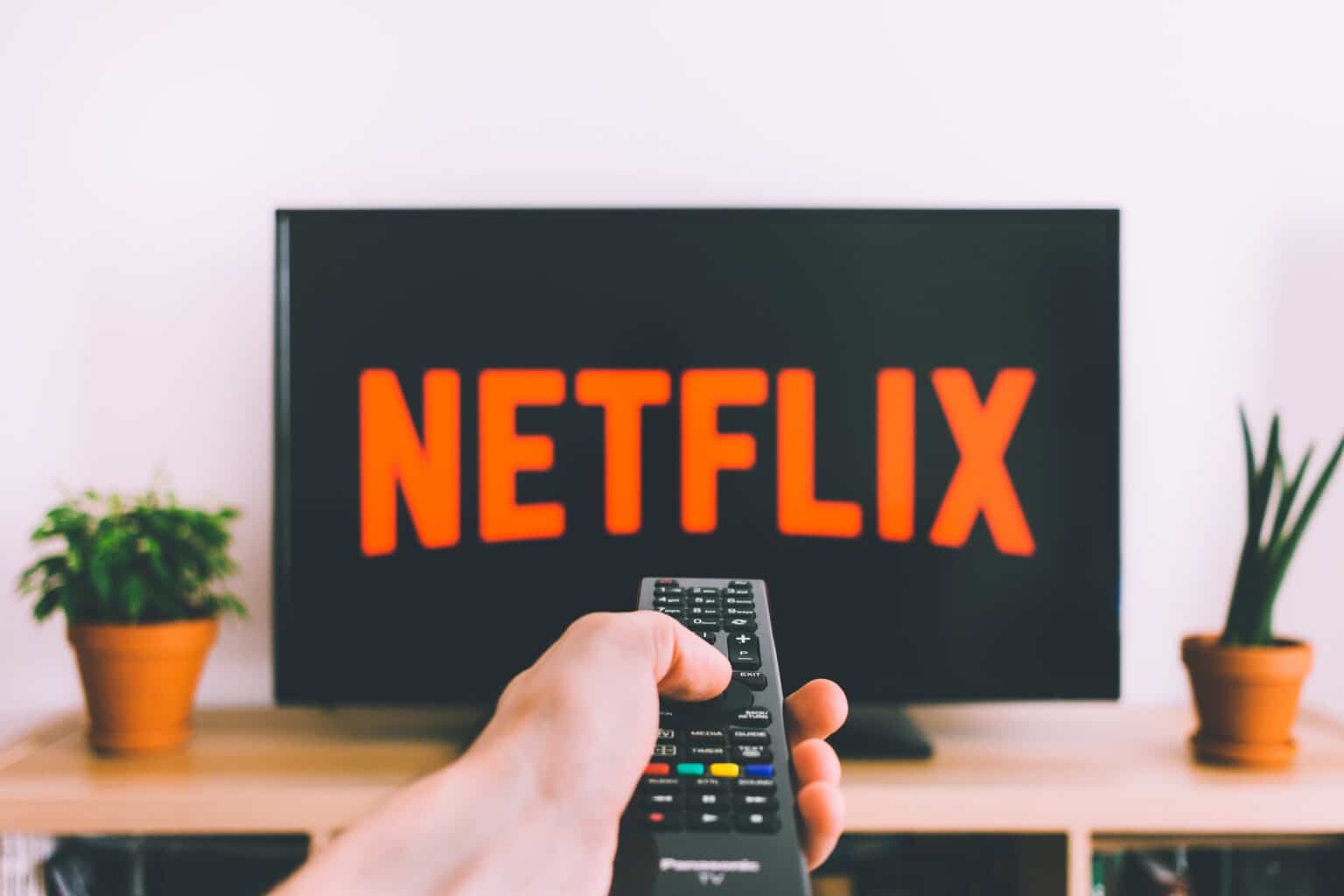 Person holding a remote in front of a TV streaming Netflix, representing a modern home theatre experience.
