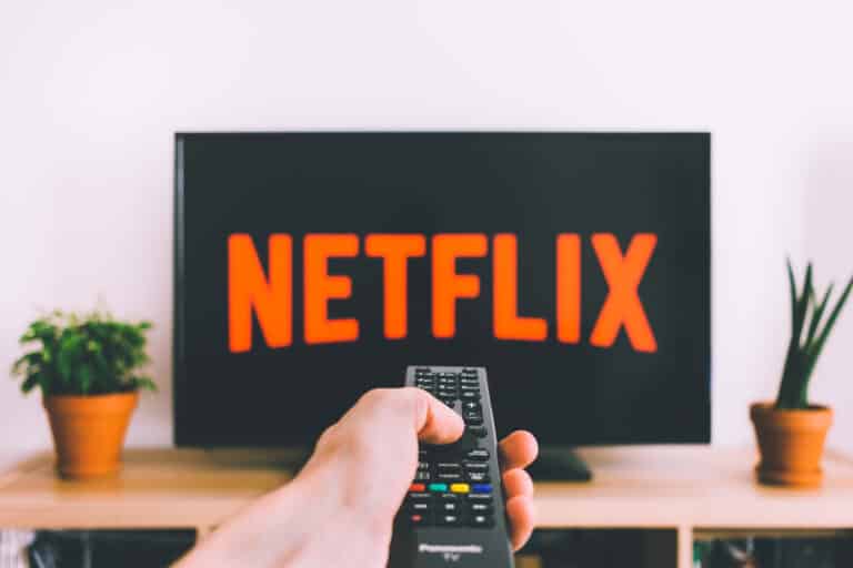 Person holding a remote in front of a TV streaming Netflix, representing a modern home theatre experience.