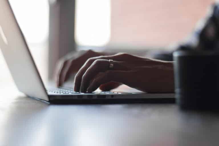 Close-up of hands typing on a laptop, emphasizing the role of strong Wi-Fi in supporting smart home technology.