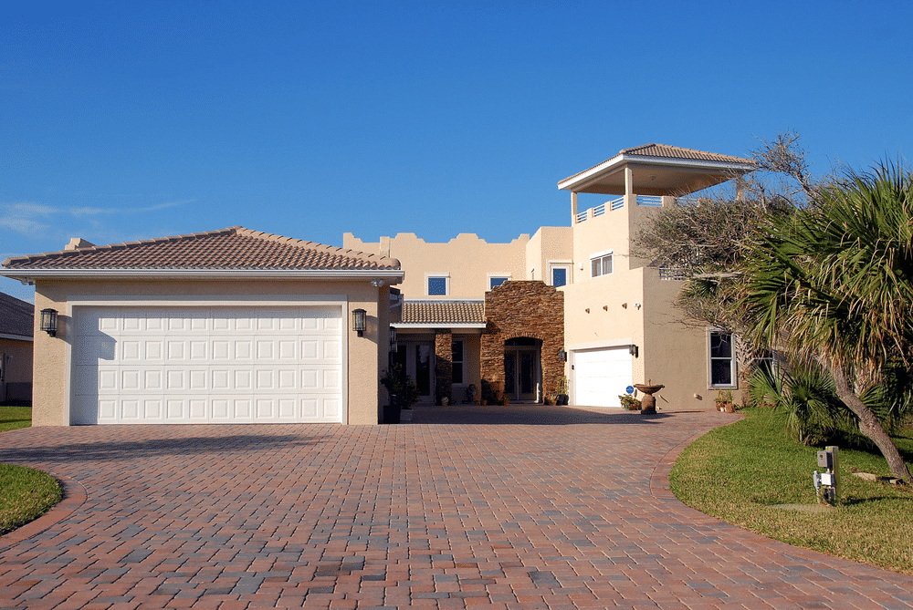 Front view of a modern home with a large driveway and garage, ideal for integration with the best security system for home.