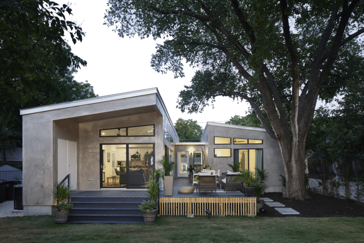 Modern home with warm lighting and large windows, showcasing the comfort and convenience of smart home technology during holiday hosting.