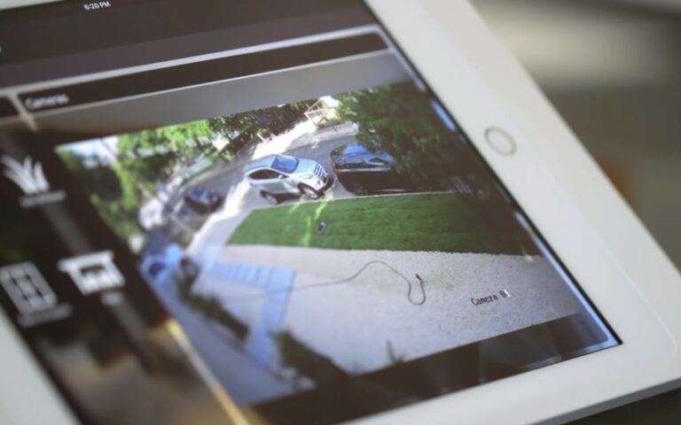 Tablet screen showing a live driveway feed from camera systems for house security monitoring.