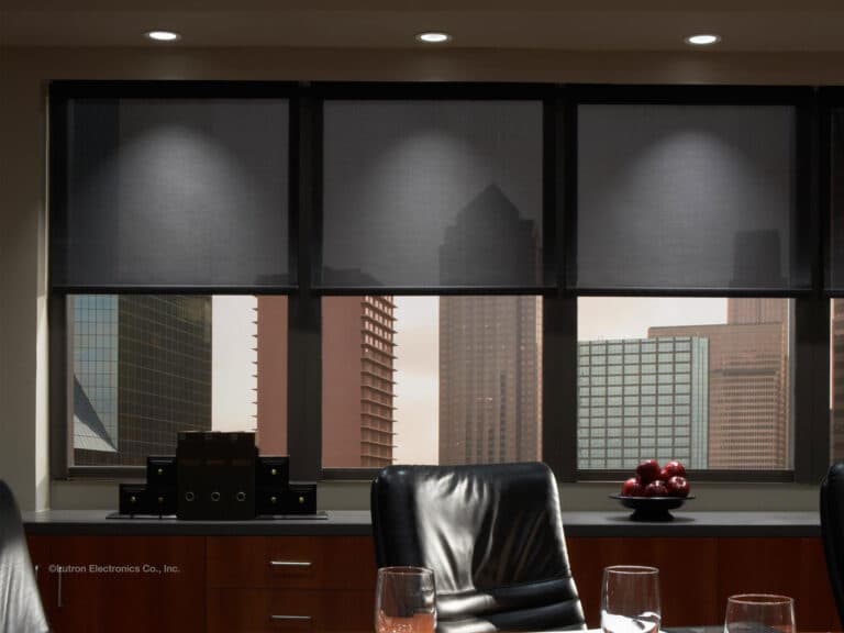 Office interior with motorized Lutron shades partially lowered, revealing a city skyline through the windows.