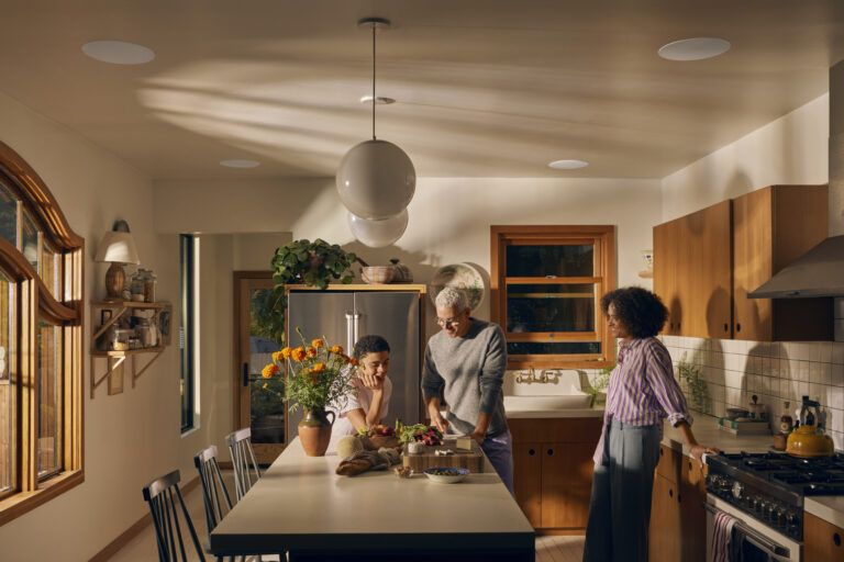 Family gathered around a modern kitchen island, enjoying conversation with integrated home audio systems in the background. Sonos Sidecar westlake automation